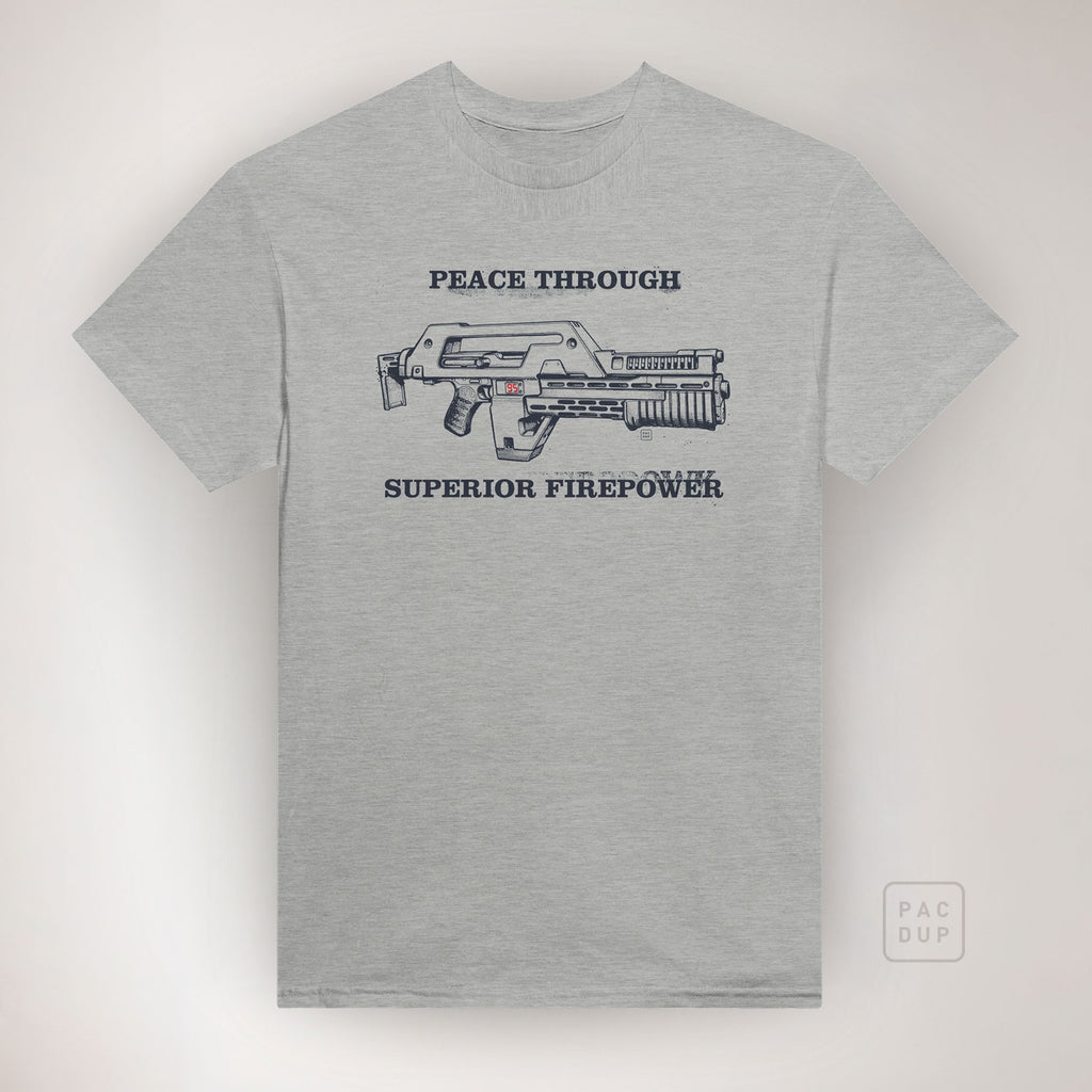 Grey Aliens-inspired T-shirt with a sci-fi rifle graphic and “Peace Through Superior Firepower” lettering, front view.